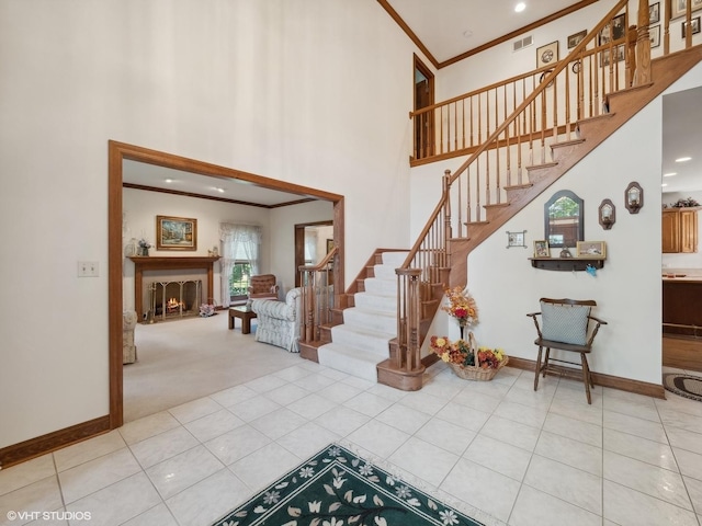 stairs with a towering ceiling, ornamental molding, and tile patterned flooring