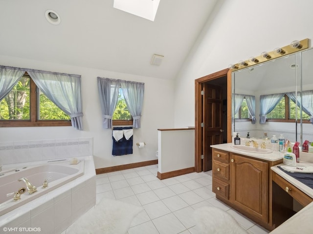 bathroom featuring a healthy amount of sunlight, vanity, vaulted ceiling with skylight, and tile patterned flooring