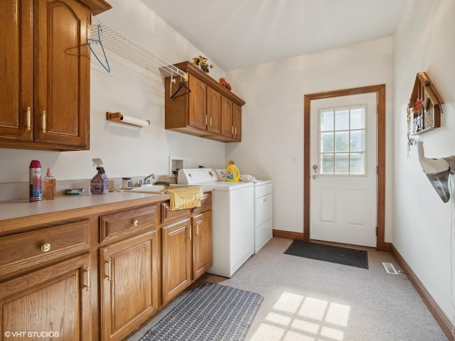 laundry area featuring sink, washer and clothes dryer, and cabinets