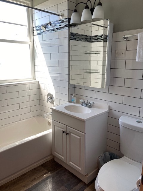 full bathroom featuring a healthy amount of sunlight, hardwood / wood-style floors, toilet, and tiled shower / bath combo