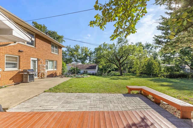 wooden deck featuring a grill, a yard, and a patio