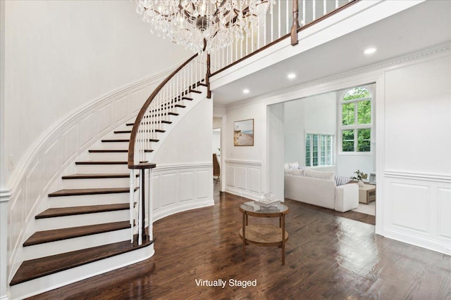 foyer featuring crown molding, dark hardwood / wood-style floors, and a towering ceiling