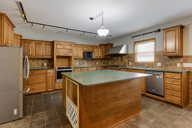 kitchen featuring tasteful backsplash, appliances with stainless steel finishes, a kitchen island, and wall chimney range hood