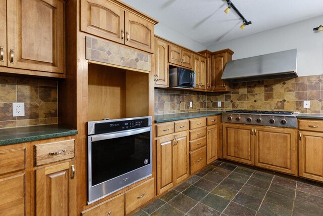 kitchen with appliances with stainless steel finishes, decorative backsplash, and wall chimney range hood