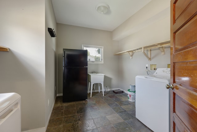 clothes washing area featuring washing machine and clothes dryer, sink, and dark tile patterned floors