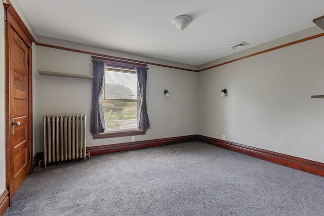 unfurnished room with radiator and carpet flooring