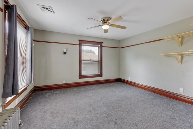 spare room with radiator heating unit, ceiling fan, and carpet flooring