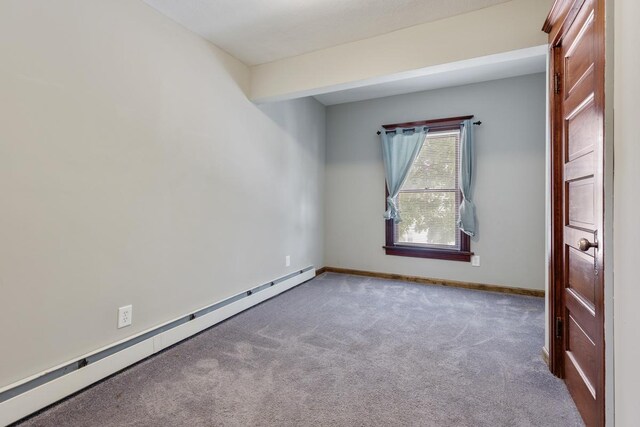 carpeted spare room with a baseboard heating unit