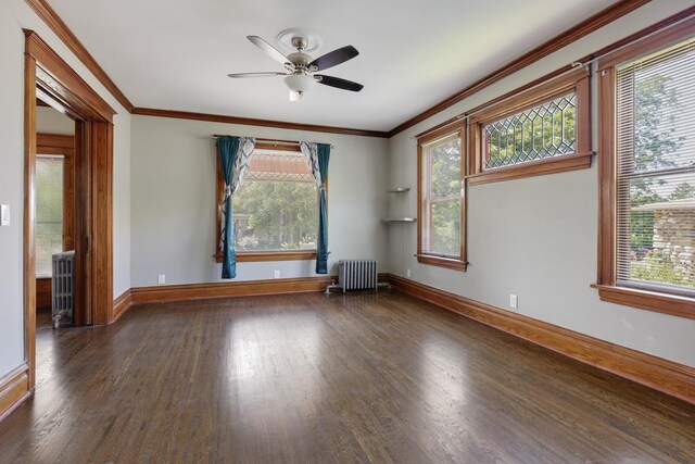 spare room with dark hardwood / wood-style floors, radiator, ornamental molding, and ceiling fan