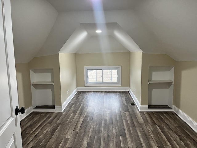 additional living space featuring built in shelves, dark hardwood / wood-style flooring, and vaulted ceiling