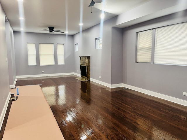 unfurnished living room featuring a fireplace, ceiling fan, and dark hardwood / wood-style flooring