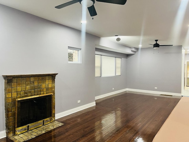 unfurnished living room with ceiling fan, a fireplace, and dark wood-type flooring