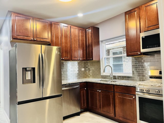 kitchen with light stone counters, sink, appliances with stainless steel finishes, and tasteful backsplash