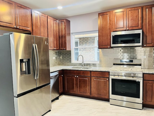 kitchen featuring light stone countertops, backsplash, stainless steel appliances, and sink