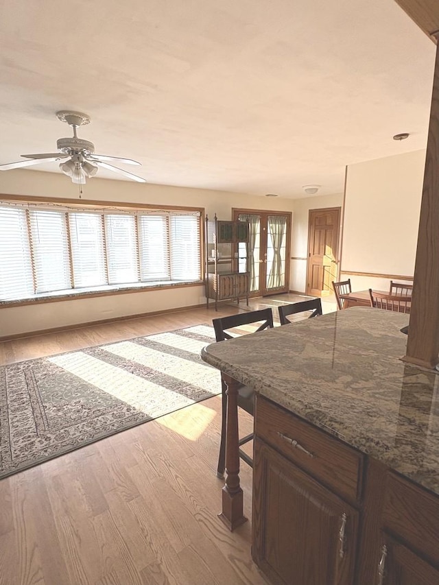 interior space with ceiling fan, french doors, stone counters, and light hardwood / wood-style floors