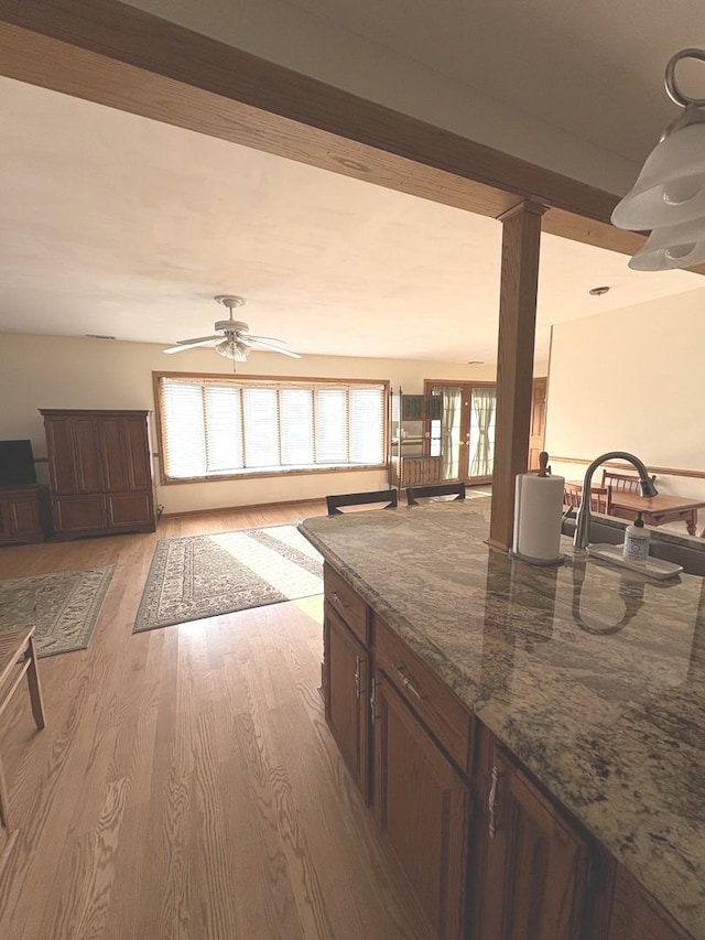 kitchen with dark stone countertops, light hardwood / wood-style flooring, sink, ceiling fan, and french doors