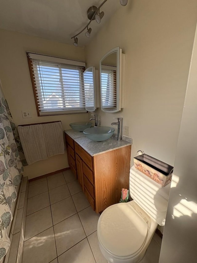 bathroom with tile patterned flooring, toilet, track lighting, vanity, and walk in shower