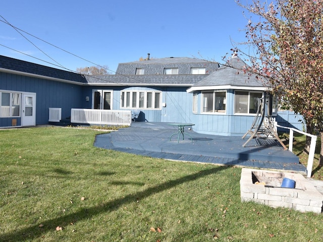 rear view of property with a sunroom, a lawn, and a wooden deck