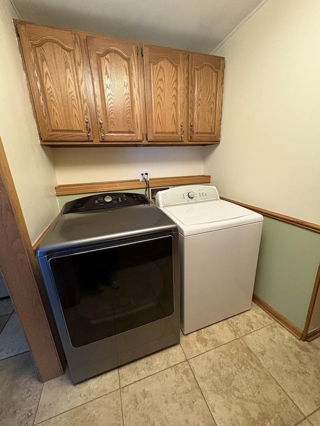 clothes washing area with light tile patterned floors, independent washer and dryer, and cabinets