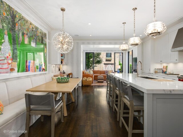 dining room with sink, a chandelier, dark hardwood / wood-style floors, and crown molding