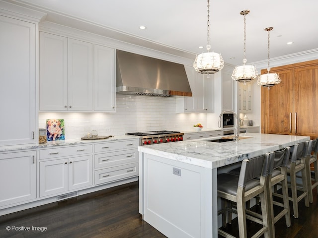 kitchen featuring dark hardwood / wood-style floors, a center island with sink, tasteful backsplash, wall chimney exhaust hood, and white cabinets