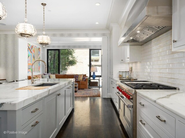 kitchen featuring hanging light fixtures, dark wood-type flooring, range with two ovens, wall chimney exhaust hood, and tasteful backsplash