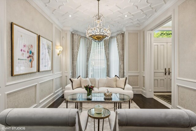 living room featuring an inviting chandelier, ornamental molding, and dark hardwood / wood-style floors