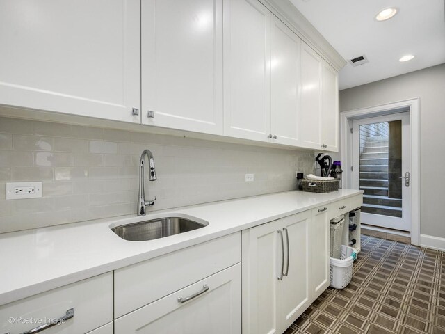 kitchen with sink, white cabinetry, dark tile flooring, and tasteful backsplash