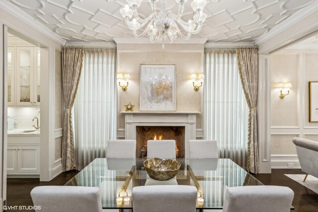 dining area featuring sink, dark hardwood / wood-style flooring, a chandelier, and ornamental molding