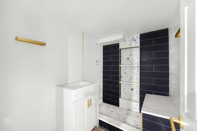 bathroom featuring a tile shower and vanity