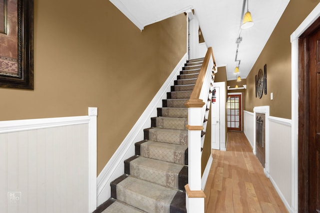 stairs featuring hardwood / wood-style floors and ornamental molding