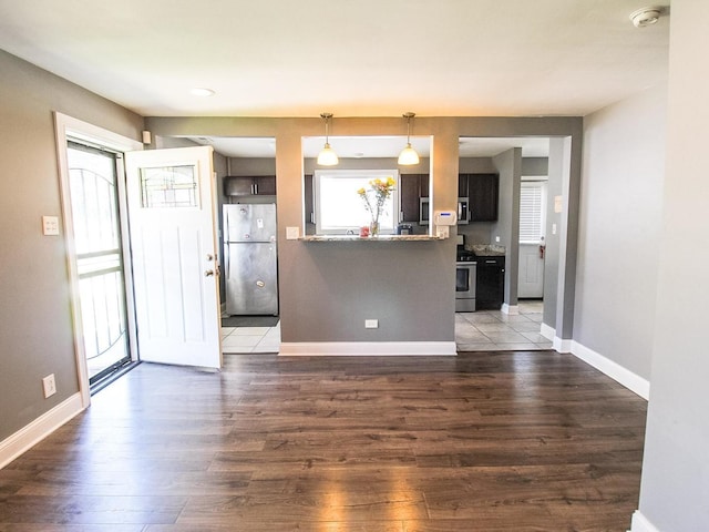 kitchen featuring kitchen peninsula, pendant lighting, stainless steel appliances, and dark wood-type flooring