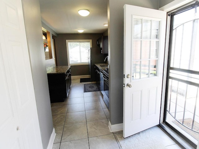 kitchen featuring sink, stainless steel fridge, stove, stone countertops, and light tile patterned floors