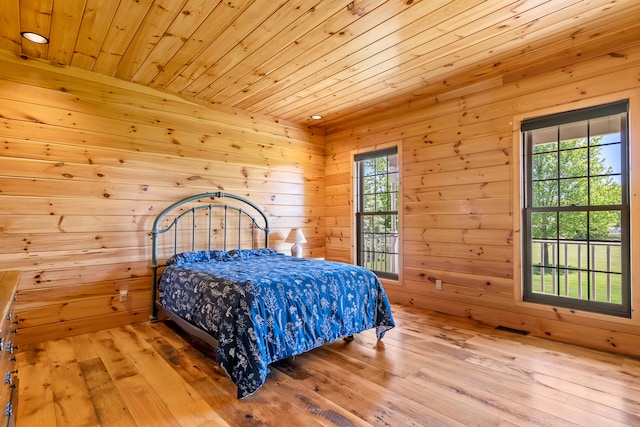 bedroom with wood ceiling, light wood-type flooring, and wood walls