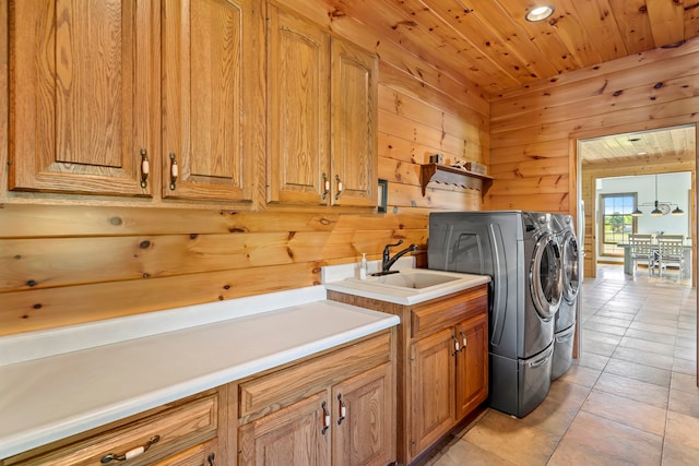 clothes washing area featuring wood walls, independent washer and dryer, wood ceiling, and light tile floors