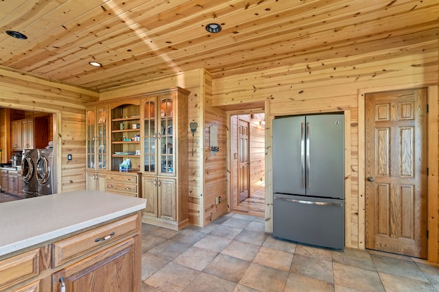 kitchen featuring light tile flooring, separate washer and dryer, stainless steel fridge, wood ceiling, and wooden walls