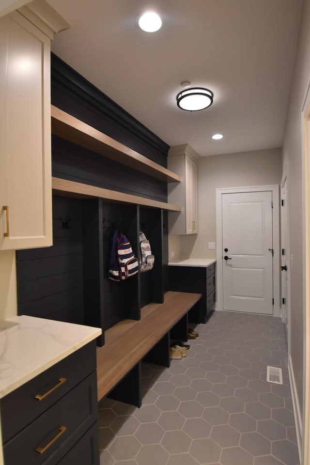 mudroom with dark tile patterned floors