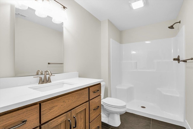 bathroom featuring tile patterned flooring, vanity, toilet, and a shower