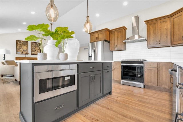 kitchen featuring pendant lighting, a center island, wall chimney exhaust hood, decorative backsplash, and appliances with stainless steel finishes