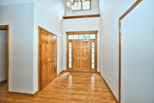 foyer featuring an inviting chandelier, light wood-type flooring, and a high ceiling