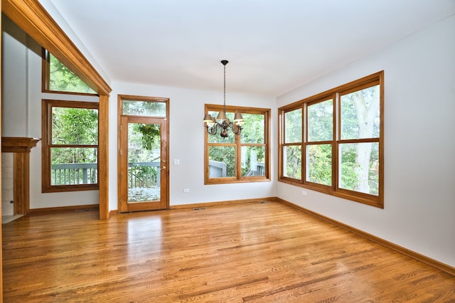 empty room with an inviting chandelier and light hardwood / wood-style floors