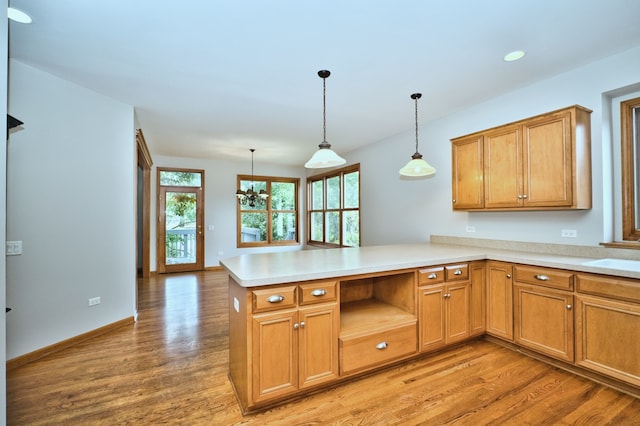 kitchen with kitchen peninsula, hardwood / wood-style floors, and decorative light fixtures