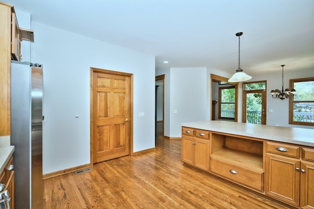 kitchen with light wood-type flooring, a chandelier, decorative light fixtures, and stainless steel refrigerator