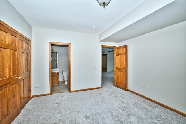 unfurnished bedroom featuring light carpet, ensuite bath, and a closet