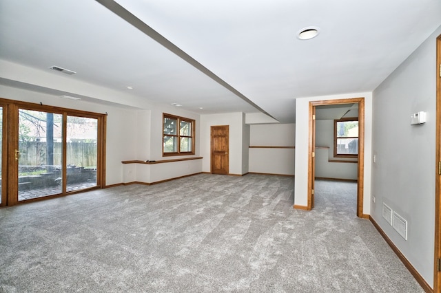 unfurnished living room with light colored carpet and a wealth of natural light