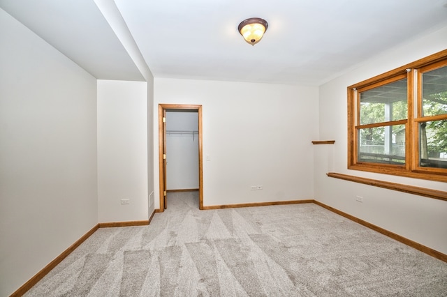 unfurnished bedroom featuring a spacious closet, light carpet, and a closet