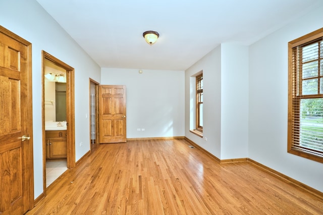 spare room with light wood-type flooring, sink, and a wealth of natural light