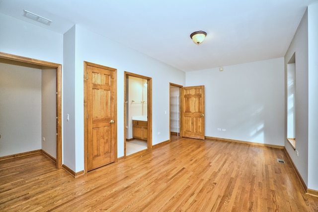 unfurnished bedroom featuring connected bathroom and light hardwood / wood-style floors