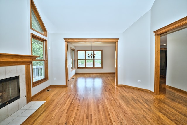 unfurnished living room featuring light wood-type flooring, vaulted ceiling, and a healthy amount of sunlight