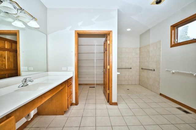 bathroom featuring a tile shower, tile patterned flooring, and vanity